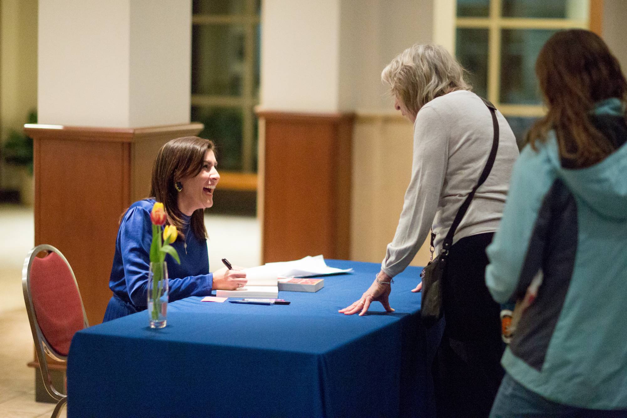 woman laughing while signing a book